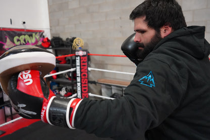 Man boxing while wearing the Collective Hoodie in Black. The logo on the upper sleeve is showing